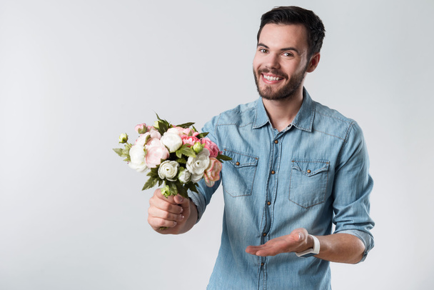 romantischer bärtiger Mann lächelt und hält einen Blumenstrauß in der Hand. - Foto, Bild