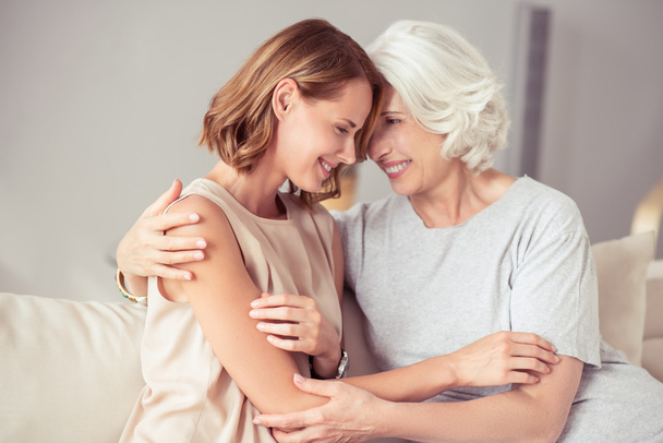 Positive aged woman and her daughter embracing - Foto, Imagem