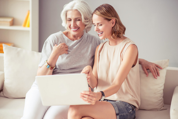 Joyful woman and her aged mother using laptop - Фото, изображение