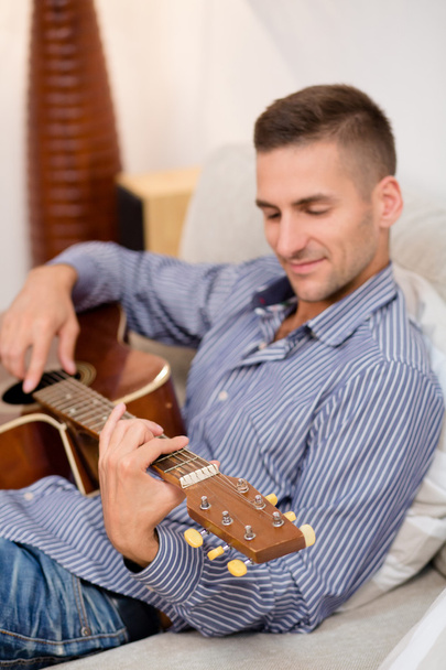 Handsome man playing guitar at home - Foto, afbeelding