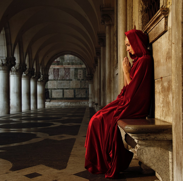 Mujer con capa roja rezando sola
 - Foto, Imagen