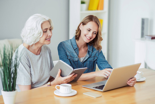 Cheerful senior woman and her daughter using laptop - Photo, image