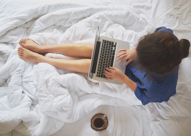 Jonge vrouw drinken koffie thuis in haar bed en haar controleren  - Foto, afbeelding