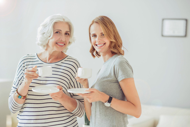 Delighted positive mother and her adult daughter drinking coffee - 写真・画像