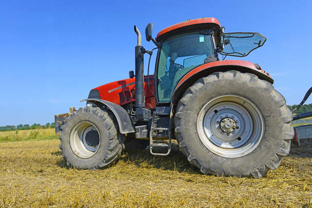 Pyörillä varustettu traktori pellolla
 - Valokuva, kuva