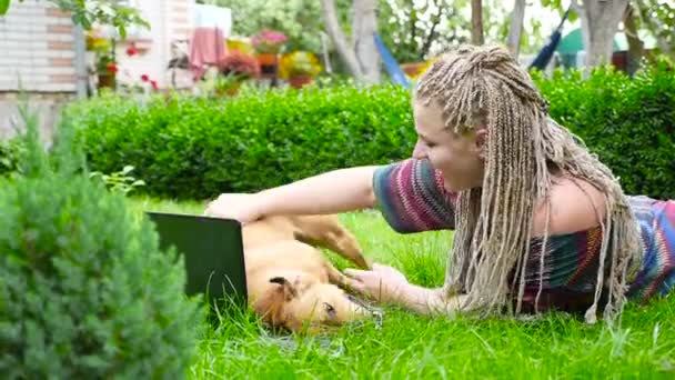 Güzel kız çimenlerin üzerinde yatıyor ve köpekle oynar. HD - Video, Çekim