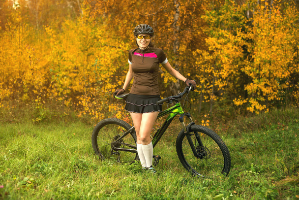 Femme faisant du vélo dans la forêt jaune d'automne sur une prairie
 - Photo, image