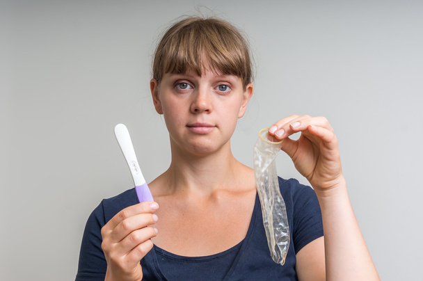 Agujero en condón y prueba de embarazo positiva
 - Foto, Imagen