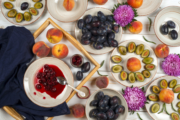 Colorato set di frutta di sfondo viola, rosso e arancione in ciotole. Prugna, pesche, anguria tagliata sopra il tavolo bianco
 - Foto, immagini