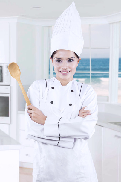 Young chef holds spoon in kitchen - Zdjęcie, obraz