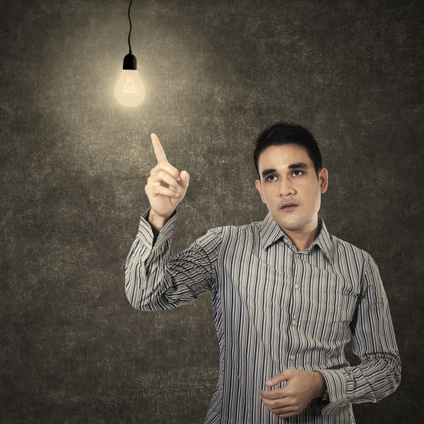 Homem apontando para lâmpada acesa em uma sala de aula
 - Foto, Imagem