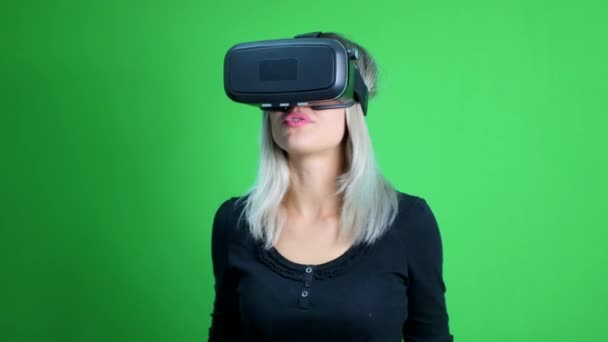 Молода жінка з головою віртуальної реальності, встановленою на зеленому екрані
. - Кадри, відео