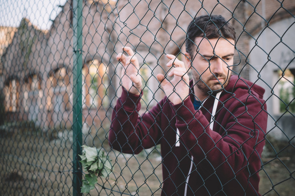Sad and troubled boy against metal fence - Photo, Image