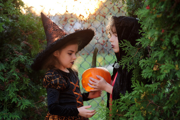 Хэллоуин. Двое детей, представляющих зловещую личность, прячутся в кустах
. - Фото, изображение