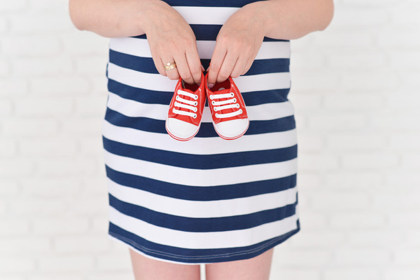 Pregnant woman with baby shoes - Zdjęcie, obraz