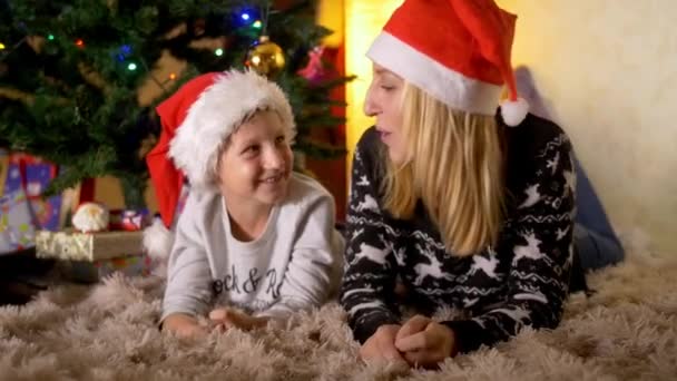 Smiling mother and happy son under christmas tree - Filmati, video