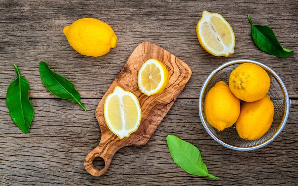 frische Zitronen und Zitronenblätter auf rustikalem Holzgrund. fre - Foto, Bild
