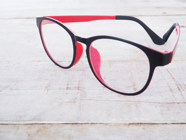 schwarze und rote Brille auf Holzhintergrund - Foto, Bild
