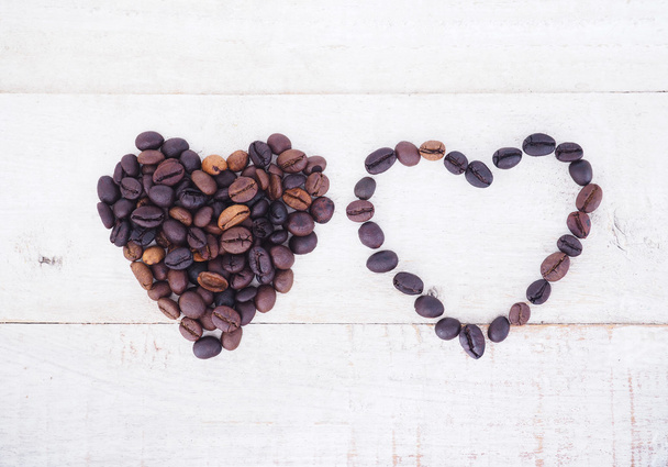 Кофейные зерна в форме сердца на деревянном фоне
.  - Фото, изображение