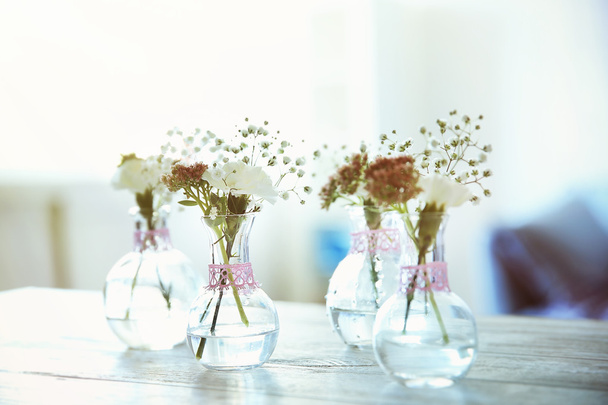 Mini glass vases with flowers on table - Valokuva, kuva