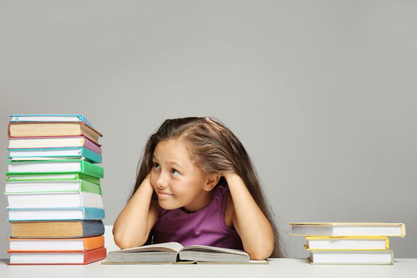 Cute girl with books on grey background - Foto, afbeelding