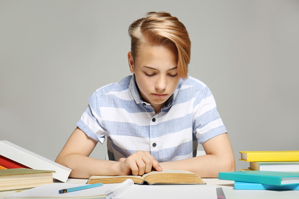 Junge macht Hausaufgaben auf grauem Hintergrund - Foto, Bild