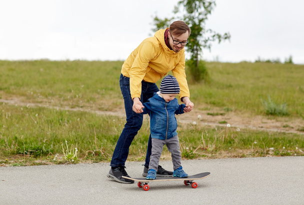 happy father and little son on skateboard - Фото, зображення