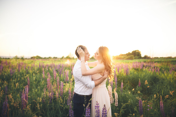 Emotional beautiful bride hugging newlywed groom from behind sunset at a field closeup - Foto, imagen