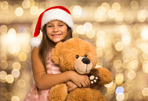 girl wearing Christmas hat holding teddy bear - Zdjęcie, obraz