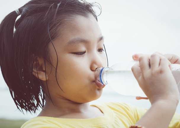 Schattig meisje is drinkwater uit de plastic fles. Schoon water wil - Foto, afbeelding