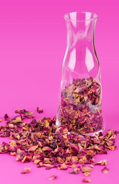 Rose petals in a glass vase over pink - Photo, image