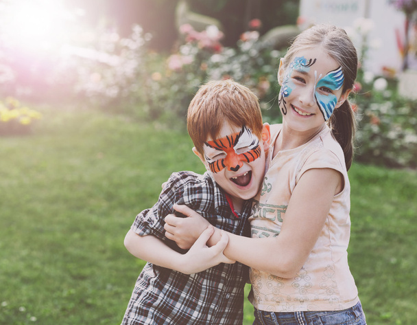 Счастливые дети, мальчик и девочка с красками для лица в парке
 - Фото, изображение