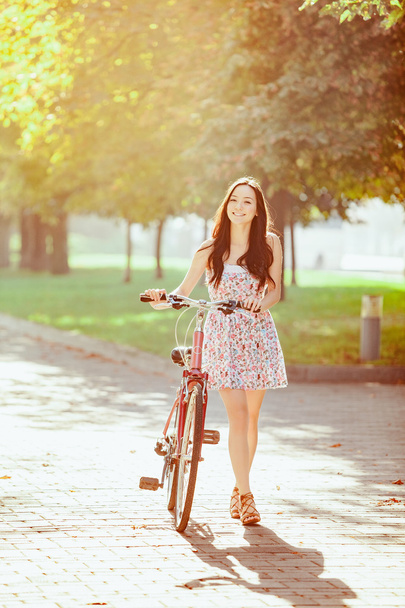 The young girl with bicycle in park - Photo, Image