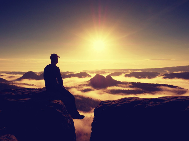 Momento de soledad. Hombre con gorra sentarse en la montaña y mirar a la niebla
 - Foto, Imagen