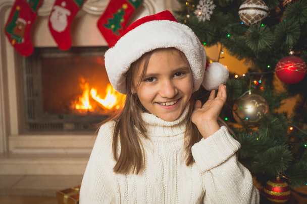 Porträt eines Mädchens in weißem Pullover und Weihnachtsmütze, das bei Burnin posiert - Foto, Bild