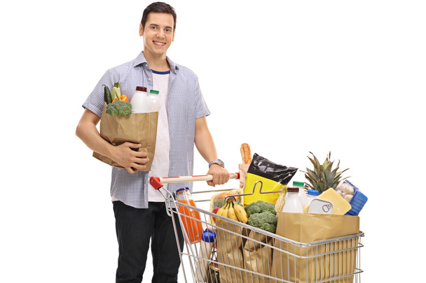 Man posing with a shopping bag and shopping cart - Foto, afbeelding