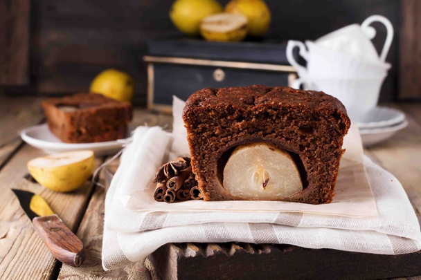 Chocolate cake with pears and cinnamon on old wooden background. Selective focus. - Photo, Image