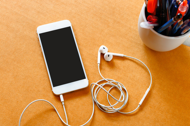 Smartphone with blank screen and earphones on wooden background - Fotografie, Obrázek