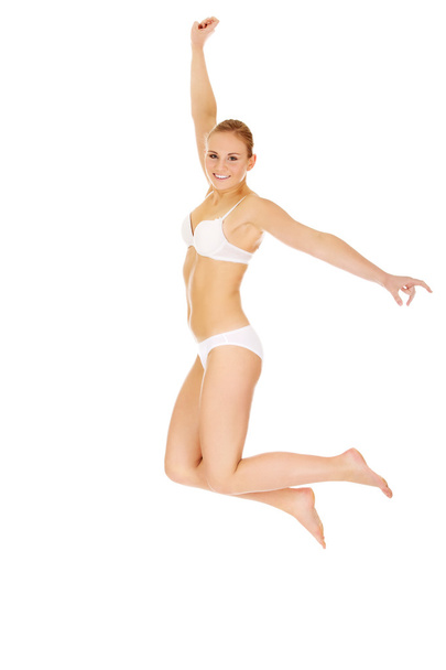 Happy young woman in white underwear jumping - Фото, изображение