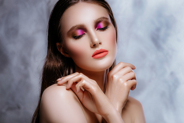 Model mit perfekter Haut und weichem Make-up posiert in einem Studio. die Brünette auf grauem Hintergrund. schönes Gesicht. - Foto, Bild