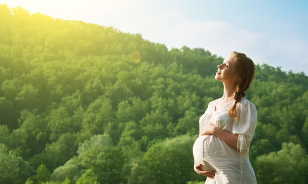 беременная женщина расслабляется и наслаждается жизнью на природе
 - Фото, изображение