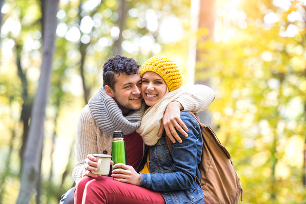 couple in autumn forest with thermos and cup - Фото, изображение