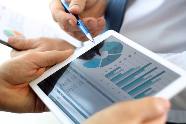 Compañeros de negocios trabajando y analizando cifras financieras en una tableta digital
 - Foto, Imagen