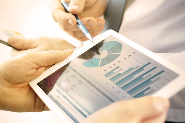 Compañeros de negocios trabajando y analizando cifras financieras en una tableta digital
 - Foto, imagen