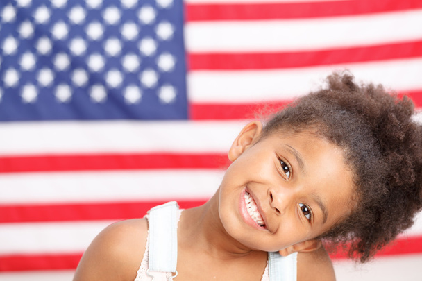 Carino ragazza in età prescolare sorridente davanti alla bandiera degli Stati Uniti
 - Foto, immagini