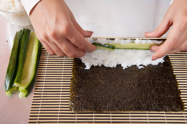 Cook making sushi rolls with cucumber - Foto, afbeelding