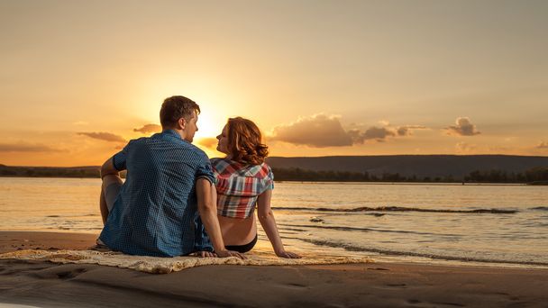 Hermosa pareja está sentada en la playa y mirando cada oth
 - Foto, imagen