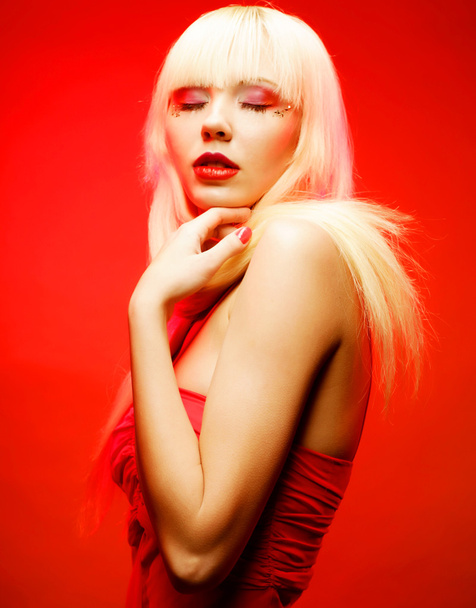Perfect blond model in red dress over red background. - Φωτογραφία, εικόνα