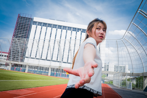 estafette, jonge zakenvrouw in pak draait op stadion track - Foto, afbeelding