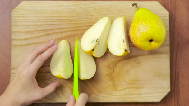 woman cuts a pear on a wooden board. - Metraje, vídeo
